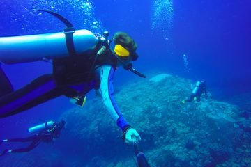 Underwater scuba diving selfie shot with selfie stick. Deep blue sea. Wide angle shot.